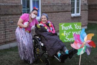 Two women dressed festively with a thank-you sign