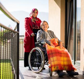 One woman helping another in a wheelchair